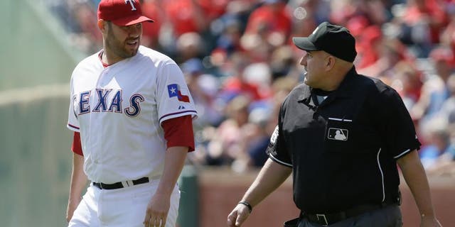 Texas Rangers starting pitcher Colby Lewis, left, discuses a call with home plate umpire Eric Cooper during the second inning of a baseball game against the Los Angeles Angels in Arlington, Texas, Saturday, Oct. 3, 2015. (AP Photo/LM Otero)