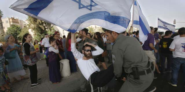 Oct. 2, 2015: Israeli border police officers carry a right wing protester after he attempted to block a road during a demonstration, a day after a drive-by shooting by suspected Palestinian gunmen killed a Jewish settler couple driving home with their children, in Jerusalem.