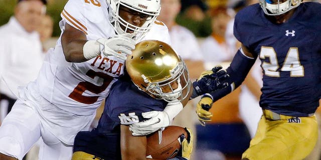 SOUTH BEND, IN - SEPTEMBER 05: Kris Boyd #2 of the Texas Longhorns tackles and dislodges the helmet of Jaylon Smith #9 of the Notre Dame Fighting Irish during the fourth quarter at Notre Dame Stadium on September 5, 2015 in South Bend, Indiana. The Notre Dame Fighting Irish won 38-3. (Photo by Jon Durr/Getty Images)