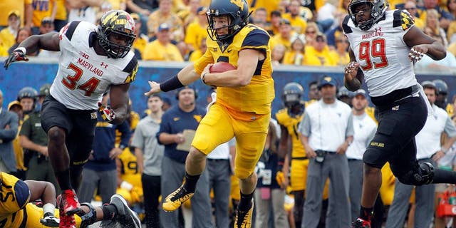 MORGANTOWN, WV - SEPTEMBER 26: Skyler Howard #3 of the West Virginia Mountaineers rushes against Quinton Jefferson #99 and Jefferson Ashiru #34 of the Maryland Terrapins during the game on September 26, 2015 at Mountaineer Field in Morgantown, West Virginia. (Photo by Justin K. Aller/Getty Images)