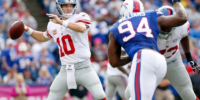 Oct 4, 2015; Orchard Park, NY, USA; New York Giants quarterback Eli Manning (10) throws a pass under pressure by Buffalo Bills defensive end Mario Williams (94) during the second half at Ralph Wilson Stadium. Giants beat the Bills 24-10. Mandatory Credit: Kevin Hoffman-USA TODAY Sports