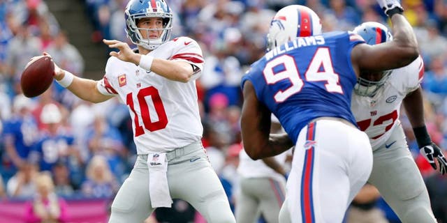 Oct 4, 2015; Orchard Park, NY, USA; New York Giants quarterback Eli Manning (10) throws a pass under pressure by Buffalo Bills defensive end Mario Williams (94) during the second half at Ralph Wilson Stadium. Giants beat the Bills 24-10. Mandatory Credit: Kevin Hoffman-USA TODAY Sports