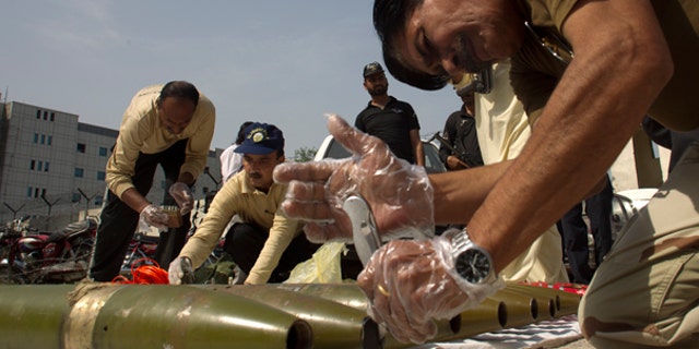 Oct. 8: Pakistani explosive experts defuse ammunition and suicide vests they recovered from a house in Islamabad, Pakistan.
