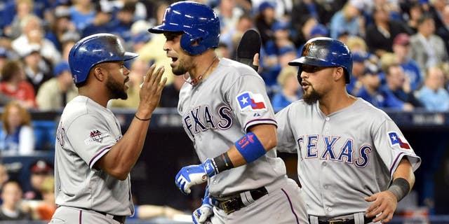 Oct 8, 2015; Toronto, Ontario, CAN; Texas Rangers catcher Robinson Chirinos (middle) celebrates with teammates Delino DeShields (left) and Rougned Odor (right) after hitting a two-run home run against the Toronto Blue Jays in the fifth inning in game one of the ALDS at Rogers Centre. Mandatory Credit: Nick Turchiaro-USA TODAY Sports
