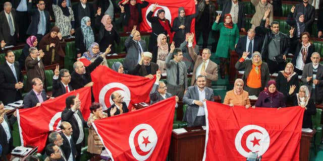 FILE - In this Sunday, Jan. 26, 2014 file photo, members of the Tunisian National Constituent Assembly celebrate the adoption of the new constitution in Tunis, Tunisia.