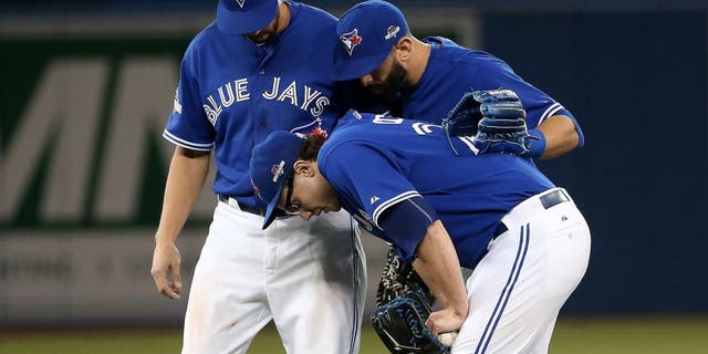 TORONTO, ON - OCTOBER 09: Brett Cecil #27 of the Toronto Blue Jays is helped by teammates after a tag out to end the top of the eighth inning against the Texas Rangers during game two of the American League Division Series at Rogers Centre on October 9, 2015 in Toronto, Canada. (Photo by Tom Szczerbowski/Getty Images)