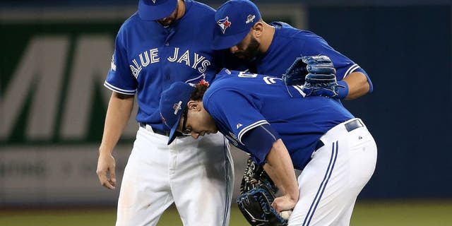 TORONTO, ON - OCTOBER 09: Brett Cecil #27 of the Toronto Blue Jays is helped by teammates after a tag out to end the top of the eighth inning against the Texas Rangers during game two of the American League Division Series at Rogers Centre on October 9, 2015 in Toronto, Canada. (Photo by Tom Szczerbowski/Getty Images)