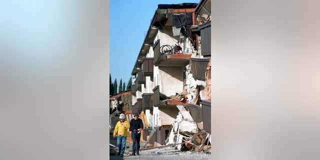 FILE - In this Jan.17, 1994, file photo, rescue workers walk past the Northridge Meadows Apartments that collapsed during the earthquake in Los Angeles.