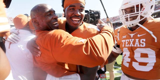 Texas head coach Charlie Strong,center left, celebrates with Tyrone Swoopes after their 24-17 win over Oklahoma in an NCAA college football game, Saturday, Oct. 10, 2015, in Dallas. (AP Photo/LM Otero)