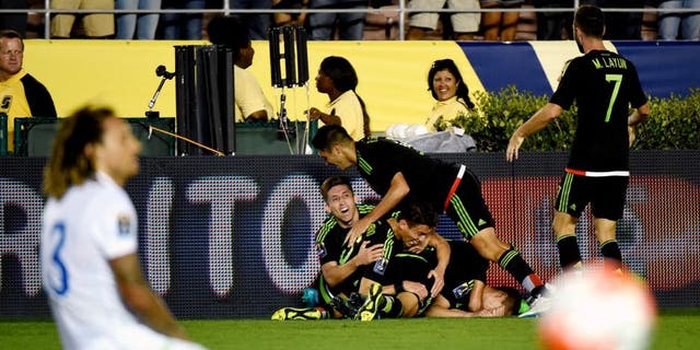 Paul Aguilar of Mexico celebrates with teammates after his game winning shot on goal as US player Jermaine Jones reacts during their 2015 CONCACAF Cup match at the Rose Bowl in Pasadena, California on October 10, 2015. The match is a playoff for the 2017 Confederations Cup. The United States lost to Mexico 3-2. AFP PHOTO / MARK RALSTON (Photo credit should read MARK RALSTON/AFP/Getty Images)