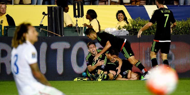 Paul Aguilar of Mexico celebrates with teammates after his game winning shot on goal as US player Jermaine Jones reacts during their 2015 CONCACAF Cup match at the Rose Bowl in Pasadena, California on October 10, 2015. The match is a playoff for the 2017 Confederations Cup. The United States lost to Mexico 3-2. AFP PHOTO / MARK RALSTON (Photo credit should read MARK RALSTON/AFP/Getty Images)