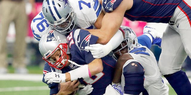 Oct 11, 2015; Arlington, TX, USA; New England Patriots quarterback Tom Brady (12) is sacked by Dallas Cowboys linebacker Rolando McClain (55) and defensive end Greg Hardy (76) at AT&T Stadium. Patriots tackle Nate Solder (77) trying to block out Hardy (76). Mandatory Credit: Erich Schlegel-USA TODAY Sports
