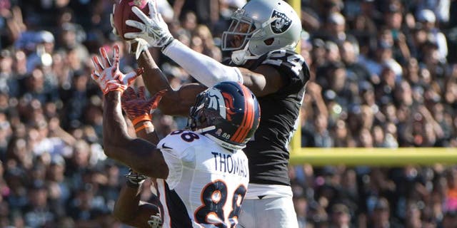 October 11, 2015; Oakland, CA, USA; Oakland Raiders free safety Charles Woodson (24) intercepts the football intended for Denver Broncos wide receiver Demaryius Thomas (88) during the third quarter at O.co Coliseum. The Raiders defeated the Broncos 16-10. Mandatory Credit: Kyle Terada-USA TODAY Sports