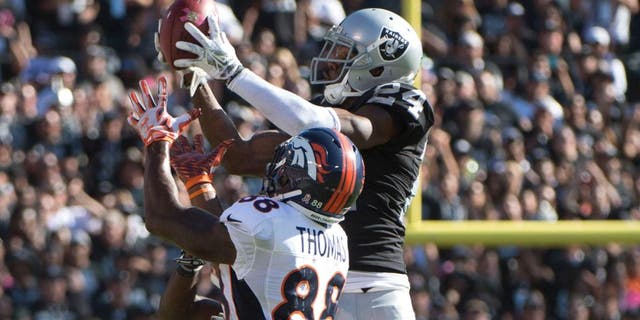 October 11, 2015; Oakland, CA, USA; Oakland Raiders free safety Charles Woodson (24) intercepts the football intended for Denver Broncos wide receiver Demaryius Thomas (88) during the third quarter at O.co Coliseum. The Raiders defeated the Broncos 16-10. Mandatory Credit: Kyle Terada-USA TODAY Sports
