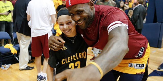 Cleveland Cavaliers forward LeBron James, right, takes a selfie with a young fan after an NBA preseason basketball game against the Atlanta Hawks, Wednesday, Oct. 7, 2015, in Cincinnati. The Hawks won 98-96. (AP Photo/John Minchillo)