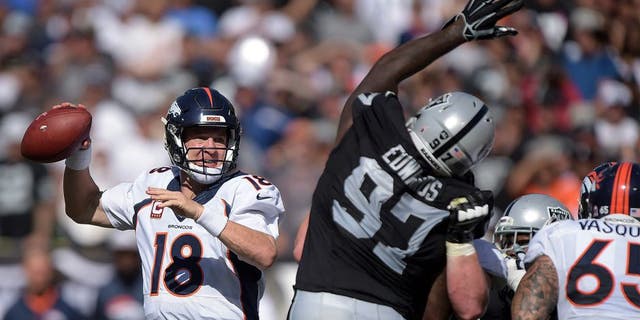 Oct 11, 2015; Oakland, CA, USA; Denver Broncos quarterback Peyton Manning (18) throws a pass under pressure by Oakland Raiders defensive end Mario Edwards Jr. (97) at O.co Coliseum. Mandatory Credit: Kirby Lee-USA TODAY Sports