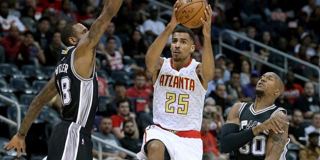 Oct 14, 2015; Atlanta, GA, USA; Atlanta Hawks guard Thabo Sefolosha (25) attempts a shot against San Antonio Spurs forward Rasual Butler (18, left) and forward David West (30) in the first quarter of their game at Philips Arena. Mandatory Credit: Jason Getz-USA TODAY Sports