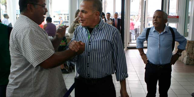 Oct. 15, 2015: A unidentified man shake hands with Venezuelan opposition leader Manuel Rosales, center, before he flies to Venezuela, at the airport near Oranjestad, Aruba.