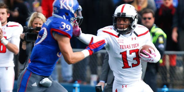 LAWRENCE, KS - OCTOBER 17: Cameron Batson #13 of the Texas Tech Red Raiders fends off Michael Glatczak #39 of the Kansas Jayhawks during the game on October 17, 2015 at Memorial Stadium in Lawrence, Kansas. (Photo by Kyle Rivas/Getty Images)