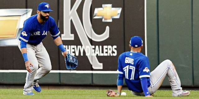 Toronto Blue Jays second baseman Ryan Goins sits on the ground and looks at the fly ball tha fell between himself and right fielder Jose Bautista, left, on a ball hit by the Kansas City Royals' Ben Zobrist in the seventh inning during Game 2 of the ALCS on at Kauffman Stadium in Kansas City, Mo., on Saturday, Oct. 17, 2015. (Shane Keyser/Kansas City Star/TNS via Getty Images)