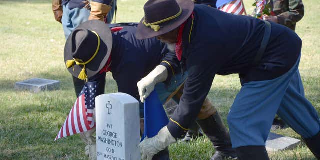 Oct. 3, 2015: Two members of the Buffalo Soldiers of the American West place flags beside the new headstone for Pvt. George Washington in Roselawn Cemetery in Pueblo, Colo.