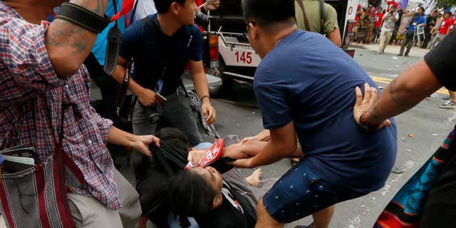 Oct. 19, 2016: A protester is helped after a Philippine National Police van, background, rammed into protesters outside the U.S. Embassy in Manila, Philippines injuring an undetermined number.