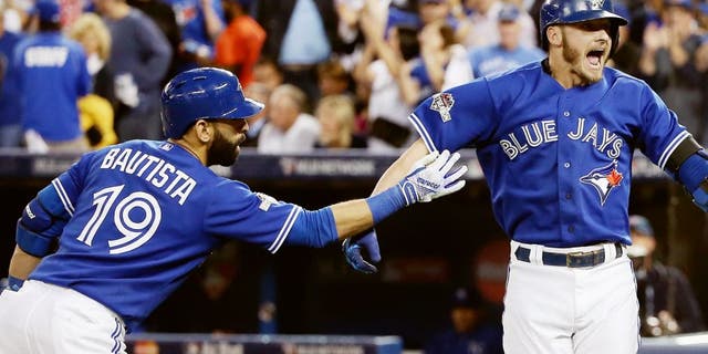 TORONTO, ON - OCTOBER 19: Josh Donaldson #20 of the Toronto Blue Jays celebrates with Jose Bautista #19 of the Toronto Blue Jays after hitting a two-run home run in the third inning against the Kansas City Royals during game three of the American League Championship Series at Rogers Centre on October 19, 2015 in Toronto, Canada. (Photo by Tom Szczerbowski/Getty Images)