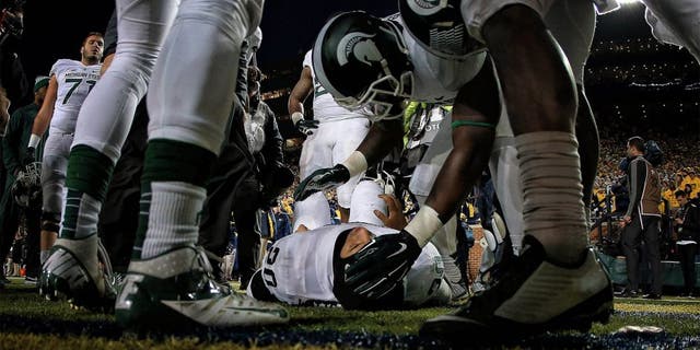 Oct 17, 2015; Ann Arbor, MI, USA; Injured Michigan State Spartans defensive back Jalen Watts-Jackson (20) is talked to by teamates before being carted off the field during the 2nd half of a game at Michigan Stadium. Mandatory Credit: Mike Carter-USA TODAY Sports