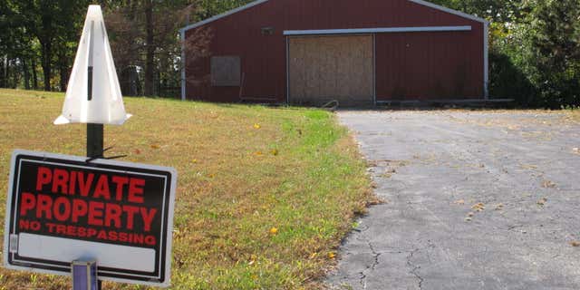 In this Tuesday, Oct. 18, 2016 photo, a private property sign guards the boarded up garage on property on Union Hill Road near the trailer where the bodies of Dana Rhoden and her children, Chris Rhoden Jr., and Hanna Rhoden, were found on April 22, three of eight family members found shot to death that day in a still-unsolved crime, in Piketon, Ohio.