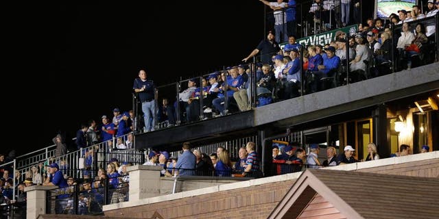 In this Oct. 20, 2015 photo, fans watch Game 3 of the National League baseball championship series between the Chicago Cubs and the New York Mets in Chicago, from the rooftop deck across the street beyond Wrigley Field's ivy-covered wall. With the massive Jumbotron now standing between the rooftop bleachers and the field, the 2015 postseason is the first for the Cubs since the team sliced into the views from the rooftops - one of the fabled experiences at this venerable old ballpark, and one in serious danger of going away for good. (AP Photo/David Goldman)