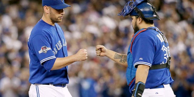 TORONTO, ON - OCTOBER 21: Toronto Blue Jays starting pitcher Marco Estrada (25) (left) gets a fist bump from catcher Dioner Navarro just before he's pulled from the game in the 7th inning. Toronto Blue Jays V Kansas City Royals in Game 5 of the American League Championship Series in MLB action at Rogers Centre. Jays win 7-1 and head back to KC for Game 6 trailing in the series 3-2. Toronto Star/Rick Madonik (Rick Madonik/Toronto Star via Getty Images)