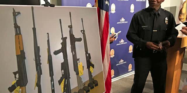 Los Angeles Police Cmdr. Horace Frank, right, shows a photo of multiple weapons found in the home of a man charged with making terrorist threats to the Islamic Center of Southern California, during a police news conference Tuesday, Oct. 25, 2016 in Los Angeles.