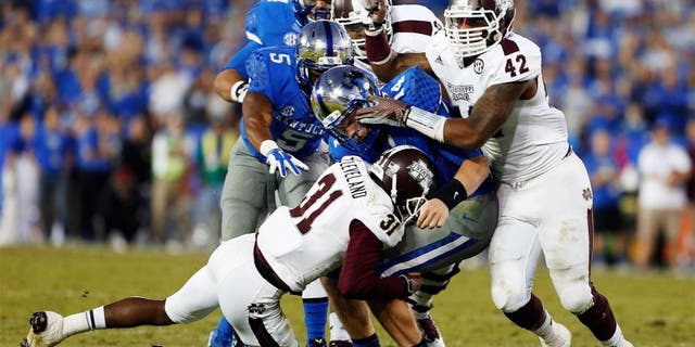 Oct 25, 2014; Lexington, KY, USA; Mississippi State Bulldogs defensive back Tolando Cleveland (31) and linebacker Beniquez Brown (42) tackle Kentucky Wildcats quarterback Patrick Towles (14) in the second half at Commonwealth Stadium. Mississippi State defeated Kentucky 45-31. Mandatory Credit: Mark Zerof-USA TODAY Sports