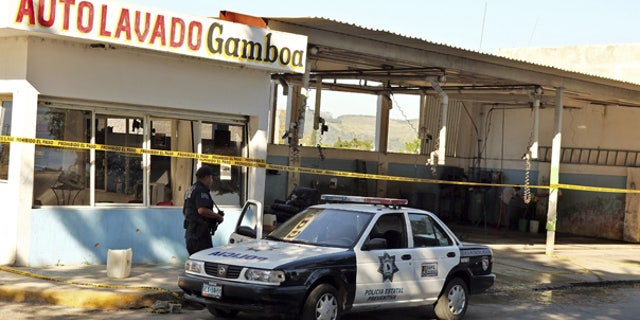 Oct. 27: A police officer is seen outside a car wash after gunmen burst into the shop and killed at least 15 people in Tepic, Mexico.