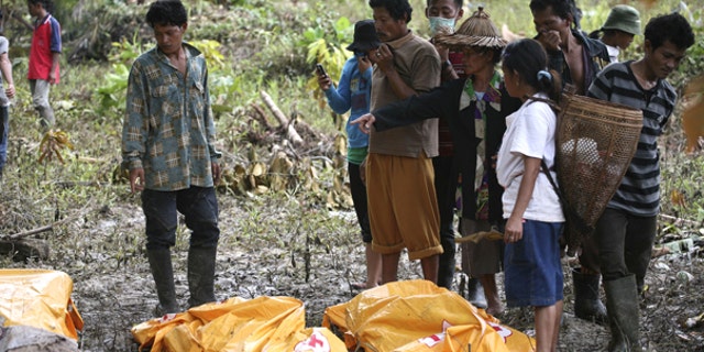 Oct. 29: Survivors look at the body of their family member who died in a tsunami at Munte, Indonesia. he toll from Monday's tsunami rose to more than 400 on Friday as officials found more bodies, and about 300 people were still missing, according to a provincial disaster management center official.