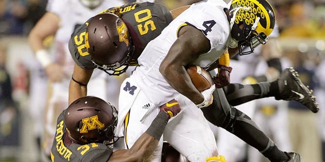 Michigan running back De'Veon Smith (4) is tackled by Minnesota's Eric Murray (31) and Jack Lynn (50) after a 15 yard catch and run during the first half of an NCAA college football game Saturday, Oct. 31, 2015, in Minneapolis.(AP Photo/Paul Battaglia)