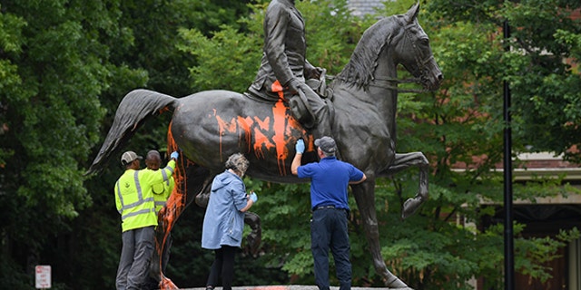 Municipal workers attempt to remove paint from a monument dedicated to Confederate soldier John B. Castleman that was vandalized late Saturday night in Louisville, Kentucky, U.S., August 14, 2017. REUTERS/Bryan Woolston - RTS1BRYR
