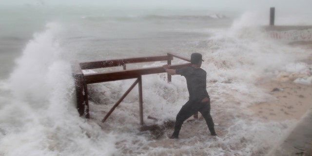 A man tries to salvage a table belonging to his restaurant before the arrival of Hurricane Maria in Punta Cana, Dominican Republic, September 20, 2017.
