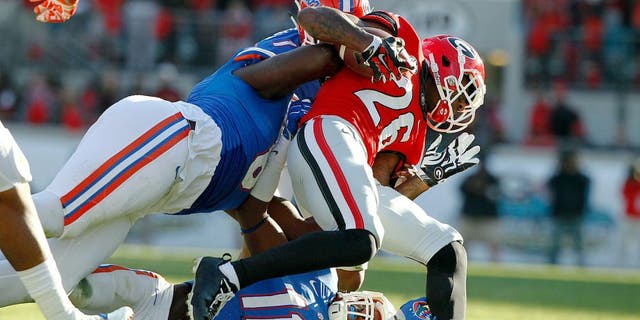 Nov 1, 2014; Jacksonville, FL, USA; Georgia Bulldogs wide receiver Malcolm Mitchell (26) is tackled by Florida Gators defensive lineman Leon Orr (8) and linebacker Neiron Ball (11) during the first half at EverBank Field. Mandatory Credit: Kim Klement-USA TODAY Sports