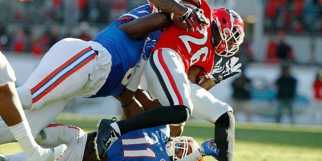 Nov 1, 2014; Jacksonville, FL, USA; Georgia Bulldogs wide receiver Malcolm Mitchell (26) is tackled by Florida Gators defensive lineman Leon Orr (8) and linebacker Neiron Ball (11) during the first half at EverBank Field. Mandatory Credit: Kim Klement-USA TODAY Sports