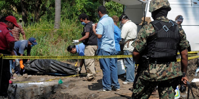 Nov. 3: A Mexican Navy soldier watch as forensic workers remove a body which was buried at a field in the town of Tuncingo, southern Mexico.