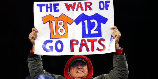 Nov 2, 2014; Foxborough, MA, USA; A fan holds up a sign about New England Patriots quarterback Tom Brady and Denver Broncos quarterback Peyton Manning during the fourth quarter of New England's 43-21 win at Gillette Stadium. Mandatory Credit: Winslow Townson-USA TODAY Sports