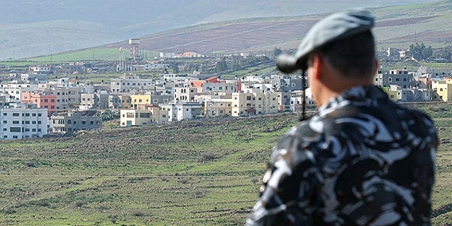 In this file photo taken on Jan. 3, 2006, a Lebanese security officer looks through binoculars at the Israeli part of the border village of Ghajar from the southern Lebanese village of Abbassiyeh in Lebanon.