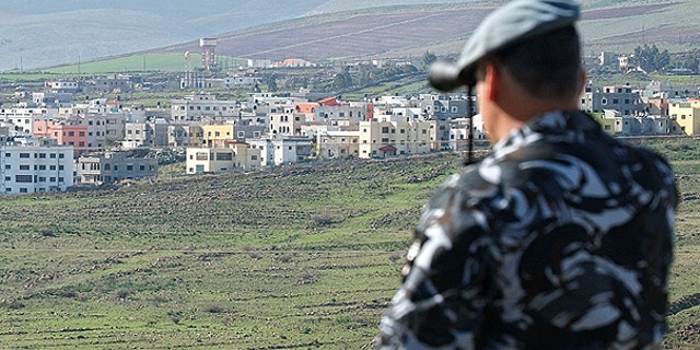 In this file photo taken on Jan. 3, 2006, a Lebanese security officer looks through binoculars at the Israeli part of the border village of Ghajar from the southern Lebanese village of Abbassiyeh in Lebanon.