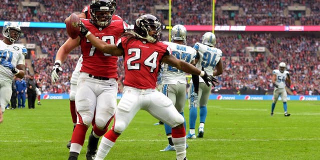 Oct 26, 2014; London, UNITED KINGDOM; Atlanta Falcons running back Devonta Freeman (24) spikes the ball after scoring on a seven-yard touchdown pass in the first quarter against the Detroit Lions as Falcons tackle Ryan Schrader (73) watches in the NFL International Series game at Wembley Stadium. Mandatory Credit: Kirby Lee-USA TODAY Sports