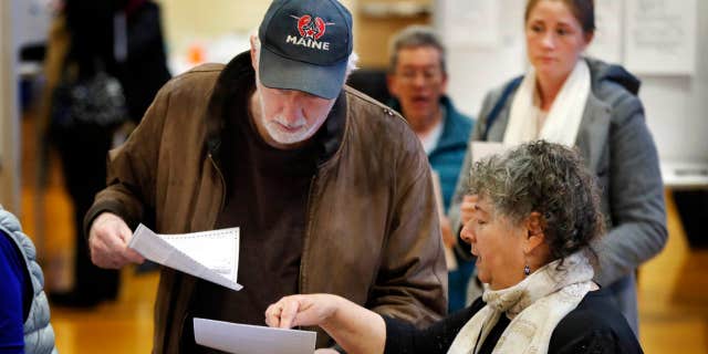 Michael Parent, left, gets instructions on submitting his ballots from warden Denise Shames while voting Tuesday, Nov. 7, 2017, in Portland, Maine.