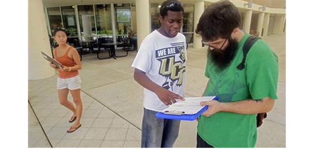 July 31, 2012: Aubrey Marks, left, watches Jordan Allen, center, as he helps student Casey Eirhstaedt, right, register to vote at the University of Central Florida in Orlando, Fla.