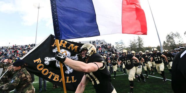 Army defensive back Caleb McNeill carries the flag of France onto the field before an NCAA college football game against Tulane, Saturday, Nov. 14, 2015, in West Point, N.Y. (AP Photo/Mike Groll)