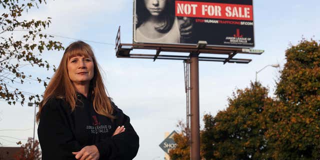 In this Oct. 27, 2015 photo, Dawn Stenberg, from the Junior League of Sioux Falls, stands near the group's anti-human trafficking billboard in Sioux Falls, S.D.