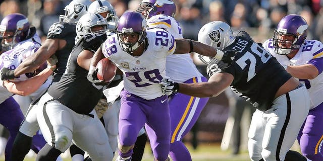 OAKLAND, CA - NOVEMBER 15: Running back Adrian Peterson #28 of the Minnesota Vikings breaks through the takcle against the Oakland Raiders in the first quarter at O.co Coliseum on November 15, 2015 in Oakland, California. (Photo by Ezra Shaw/Getty Images)